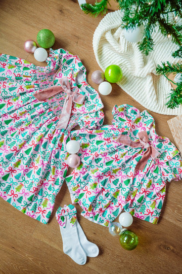 Children's Christmas-themed outfit with a dress, bloomers, and socks on a wooden surface.