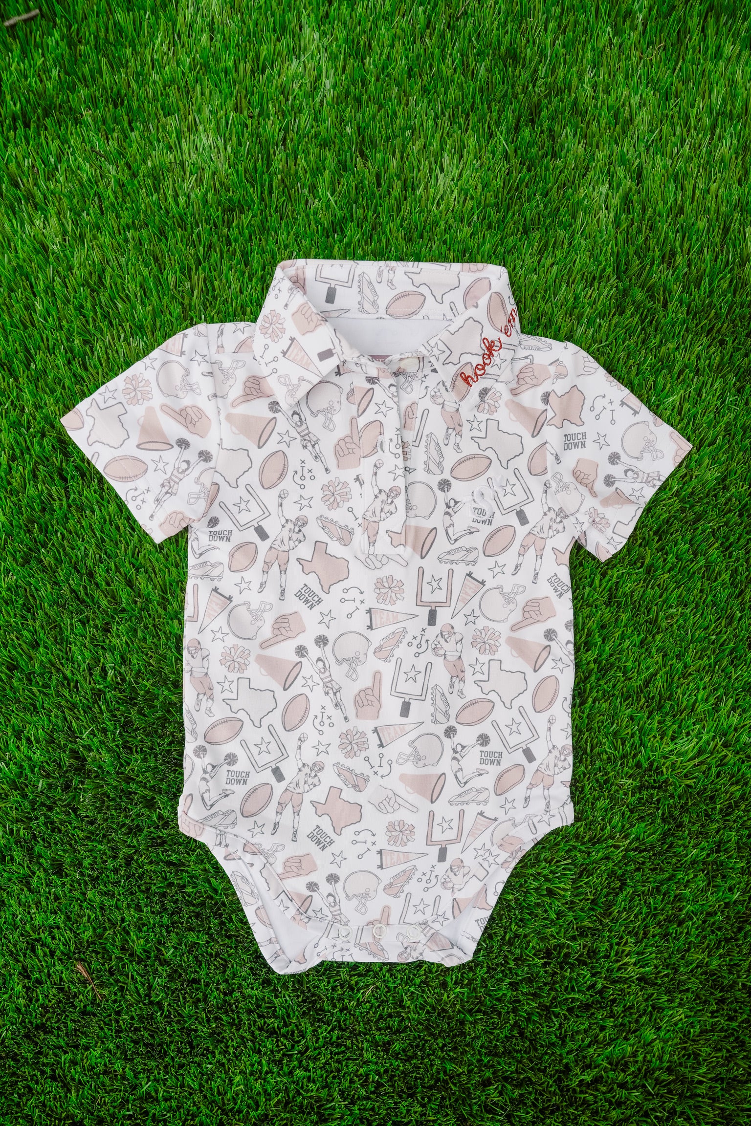 Baby onesie with football pattern on grass