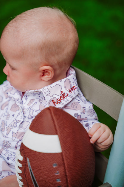 Baby holding a football with a football shirt outdoors