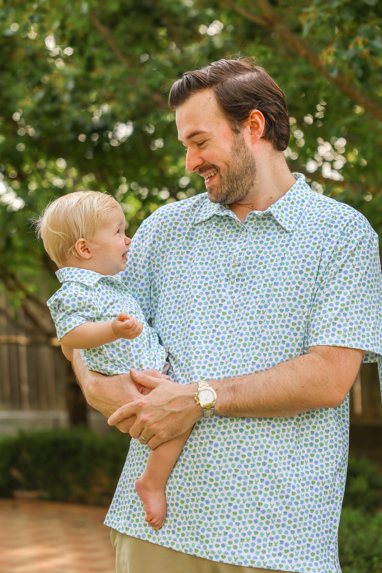 Father and son wearing matching Dapper Dog polo shirts and baby polo onesie outdoors
