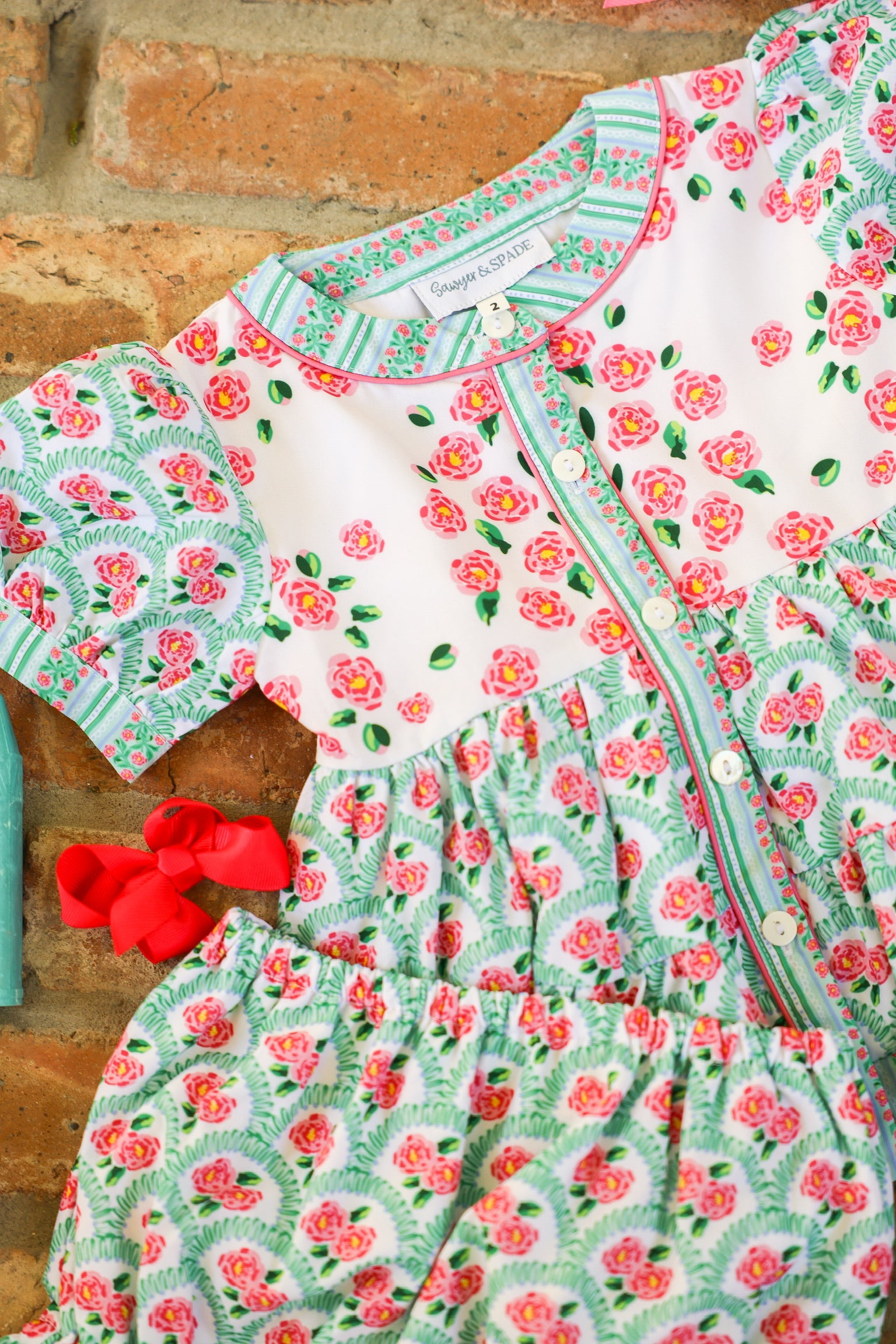 Detail of the Garden Party baby girl diaper set featuring the pink and green floral print and button-front design.