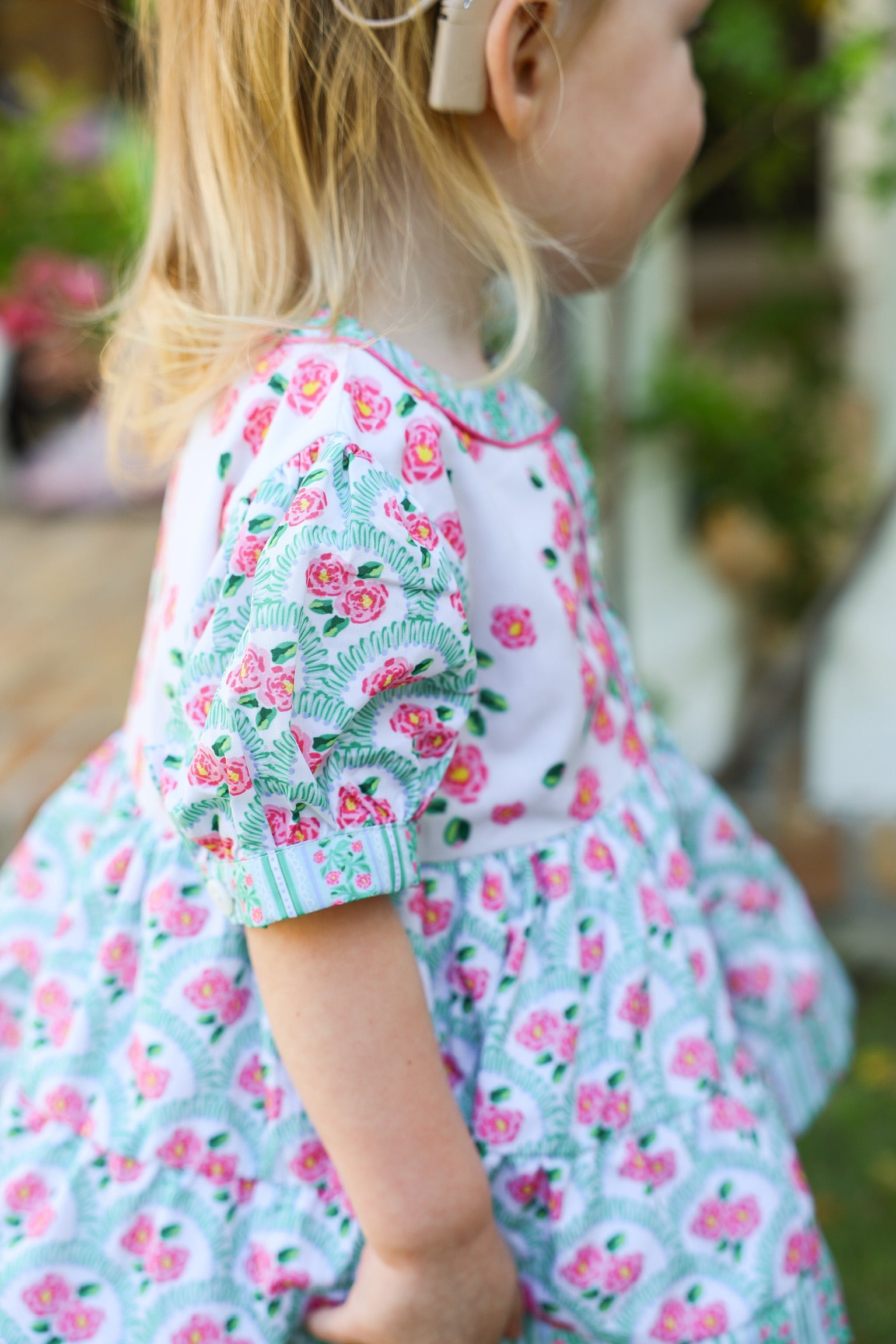 Close-up of the Garden Party girls pink floral dress sleeve with green trim and floral print
