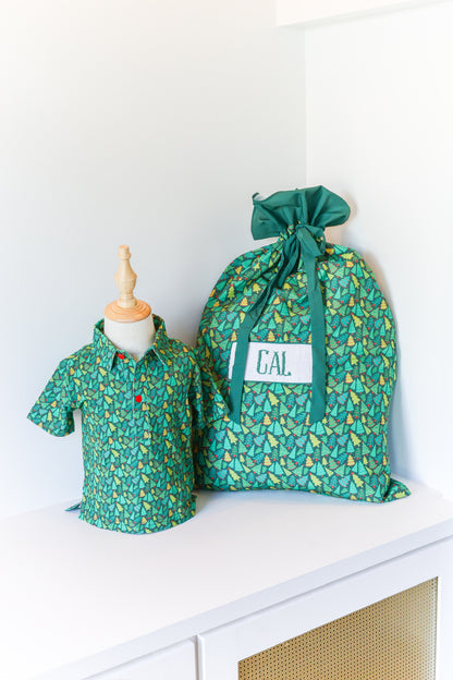 A green patterned drawstring storage bag with a white label reading 'CAL' sits on a white shelf next to a matching green patterned short-sleeve shirt displayed on a mannequin torso.