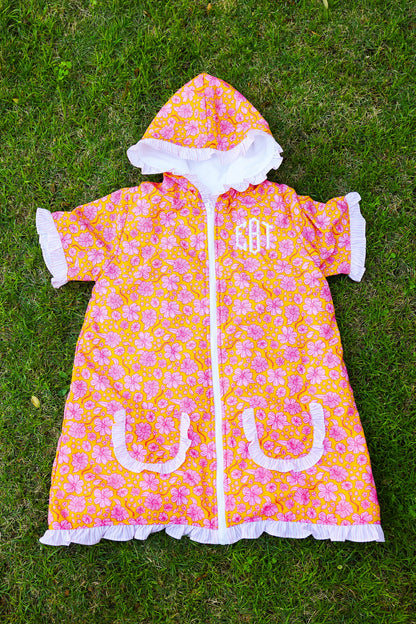 Pink floral kids hooded towel poncho with ruffle trim and front pockets on grass