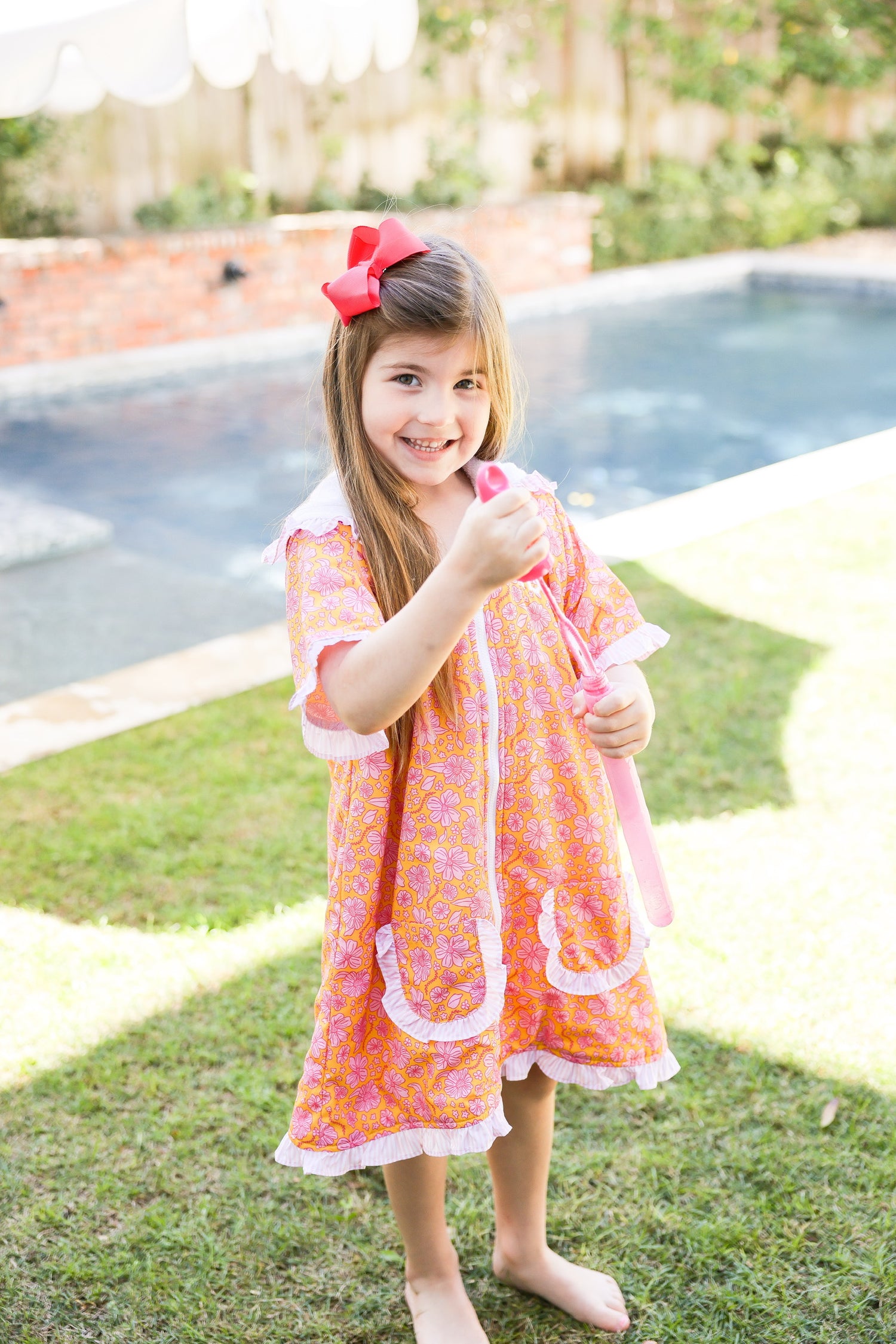 Girl wearing a pink floral kids hooded towel poncho by the pool