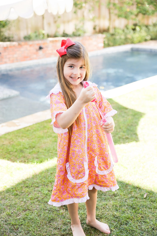 Girl wearing a pink floral kids hooded towel poncho by the pool