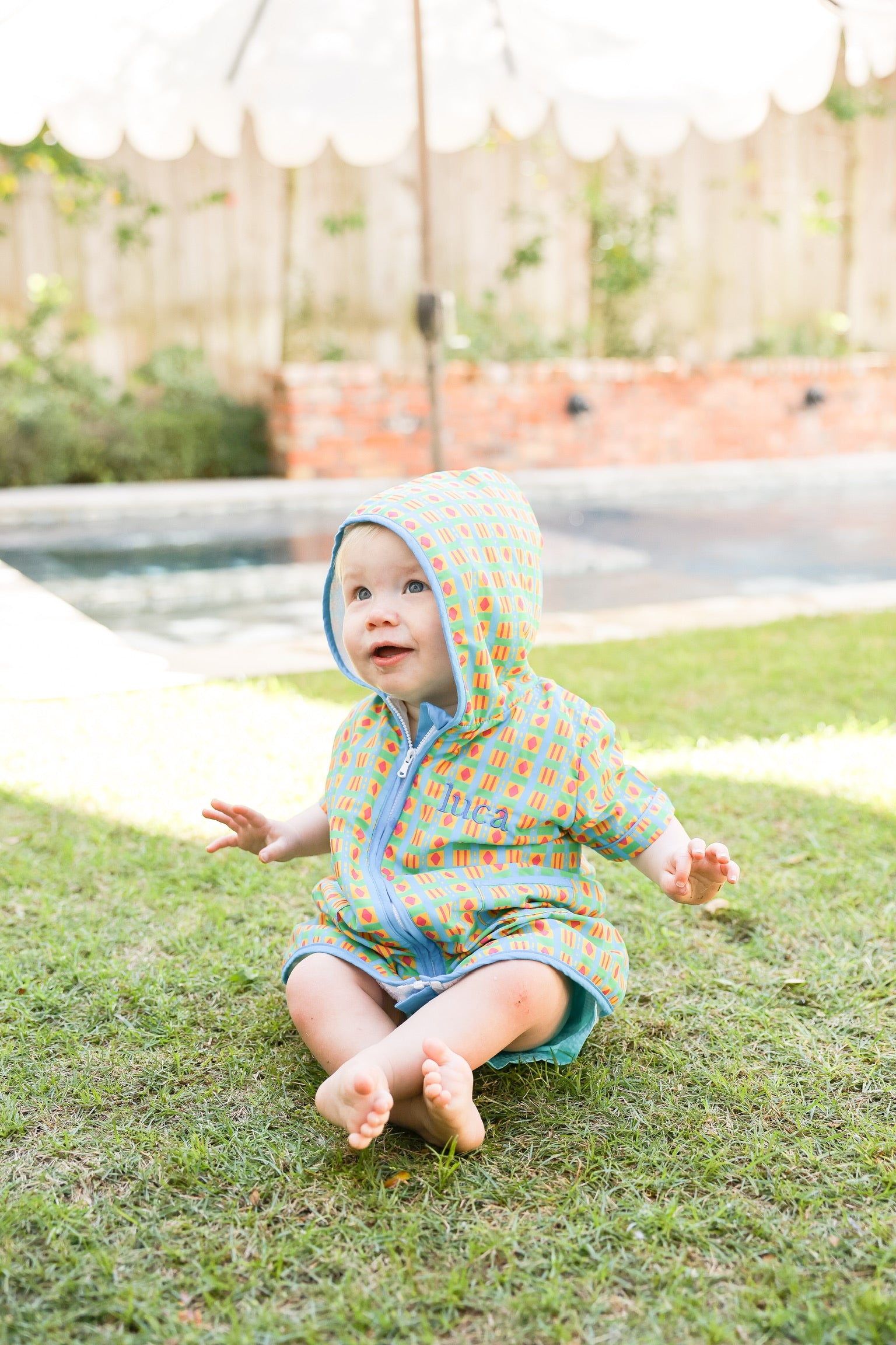 Child wearing the Retro Splash hooded towel poncho by the pool after swimming.
