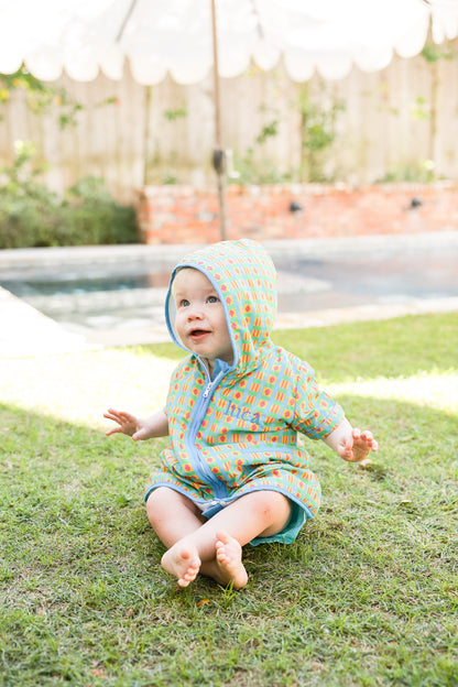 Child wearing the Retro Splash hooded towel poncho by the pool after swimming.